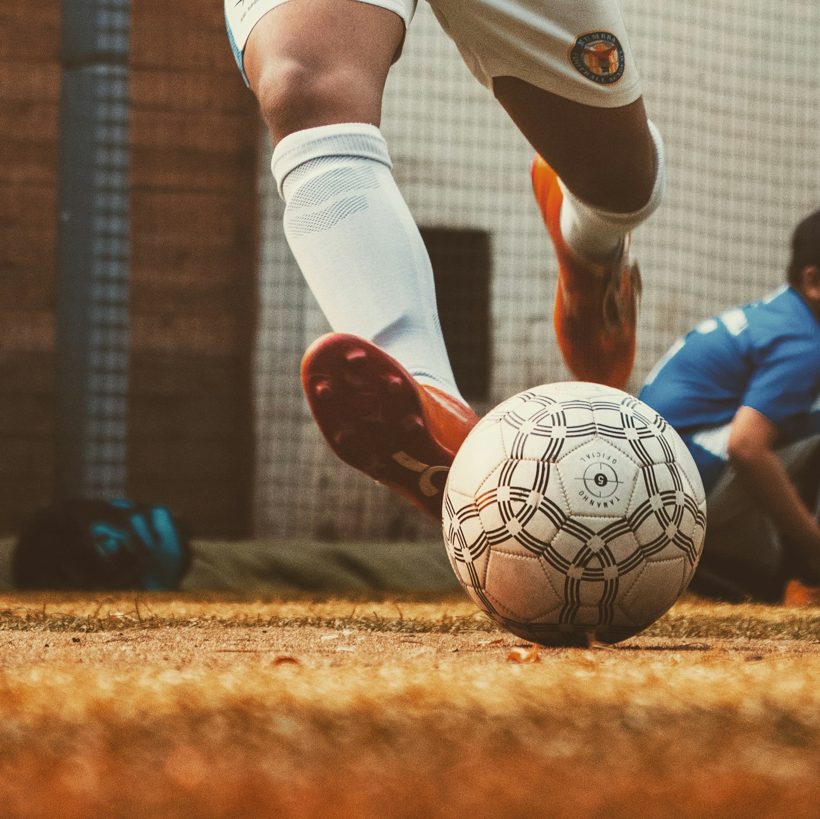Player striking a soccer ball on the pitch